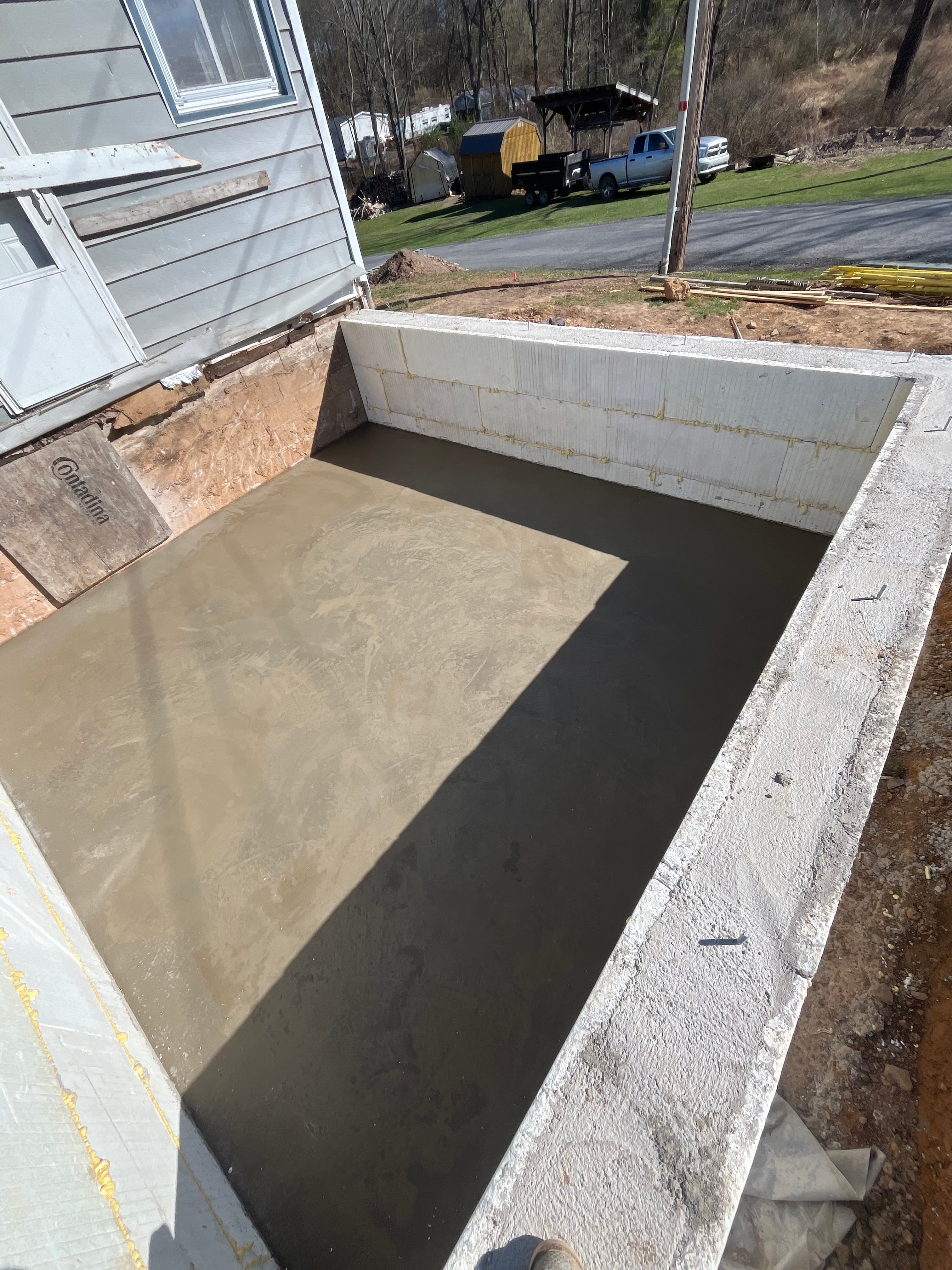 Smooth, freshly poured concrete slab within a concrete foundation at a residential construction site.